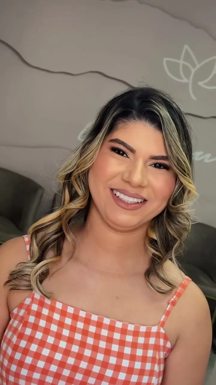 Cliente sorrindo com cabelo em ondas e mechas