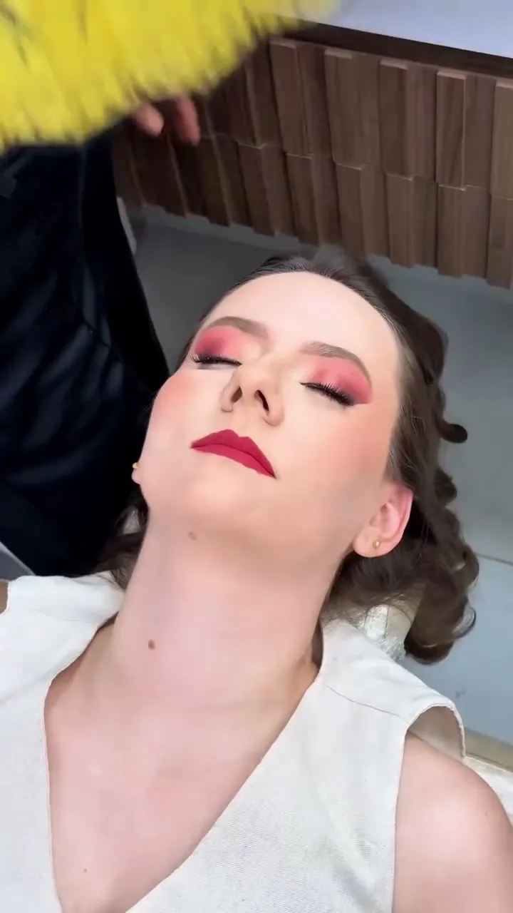 Cliente de olhos fechados com sombra rosa e batom vermelho